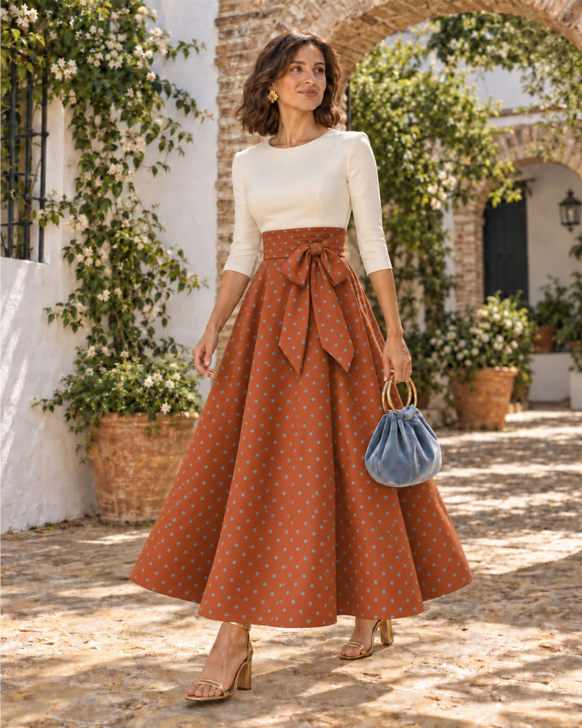 Invitada de boda con bolso Velvet en terciopleo azul y aros dorados